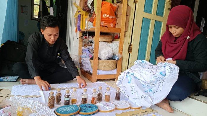 Miss Reni  (30) dan timnya, Rahmat Amin (25) mengangkat kain sasirangan yang sudah diberi pewarna alami, di SBK Sasirangan di Peta SBK Sasirangan Jalan  Sukarelawan Gang. Al-Manar No.2, Guntung Payung, Kecamatan Landasan Ulin, Kota Banjarbaru, Kalimantan Selatan