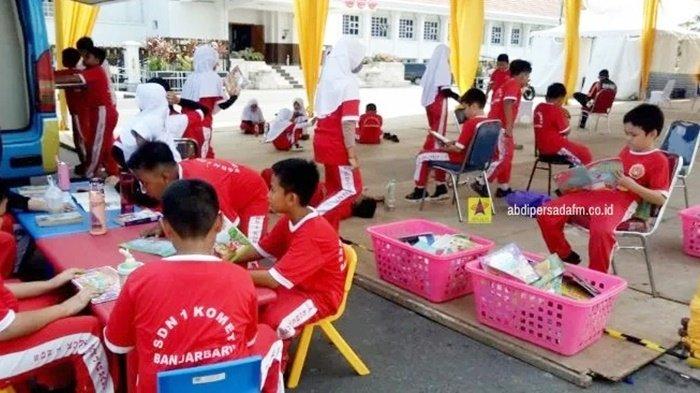 Murid-murid SD asyik masing-masing membaca buku yang dipinjamnya dari Perpustakaan Keliling (Pusling) Dinas Perpustakaan dan Kearsipan (Dispersip) Provinsi Kalimantan Selatan di Kalsel Expo 2023, Lapangan Murdjani, Kota Banjarbaru.