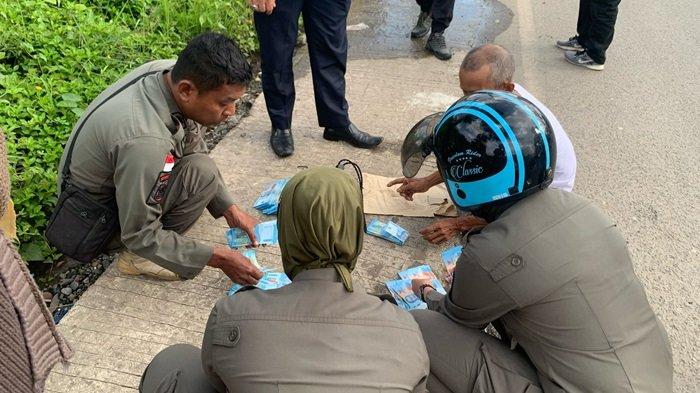 UANG BERSERAKAN - Anggota Satpol PP Kabupaten Balangan mengumpulkan uang berserakan di Jalan A Yani, Kecamatan Paringin Selatan, Kabupaten Balangan.