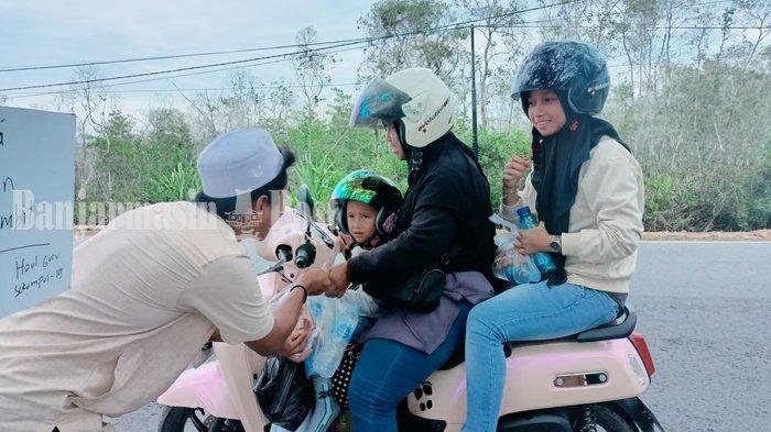 Pemberian paket snack kepada para jemaah haul Abah Guru Sekumpul 2024 yang melintas.