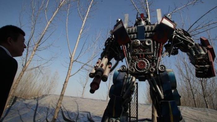 Seorang pria sedang memandangi robot Optimus Prime, salah satu karakter dalam film Transformers, yang dibuat para petani China dengan bahan onderdil mobil bekas.