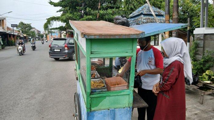 LAYANI PEMBELI - Seorang pedagang kupat blengong yang mangkal di Jalan Sawo Barat Kelurahan Kraton, Kota Tegal, tengah melayani pembeli, Minggu (1/6/2025). Jalan Sawo Barat menjadi sentra penjualan kupat blengong. Pedagang mangkal menggunakan gerobakan.