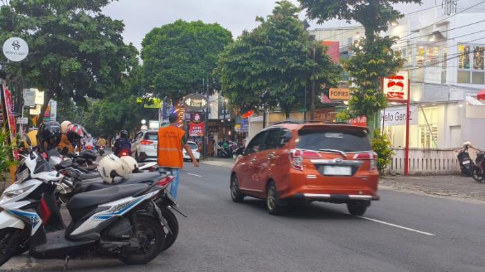 ATUR PARKIR - Petugas parkir berseragam membantu pengendara di Jalan HR Boenyamin Purwokerto, Kabupaten Banyumas, Selasa (15/7/2025).