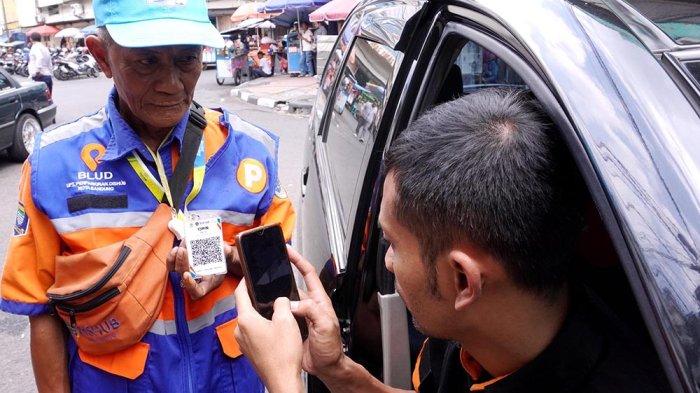 Seorang warga menggunakan akses pembayaran digital untuk parkir. Dishub Banyumas sedang mengembangkan aplikasi parkir digital yang akan menjadi basis data resmi, di mana jukir yang tidak terdaftar akan dianggap ilegal.