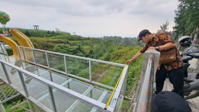 Petugas Dinas Pekerjaan Umum (DPU) Kabupaten saat memeriksa jenis kaca yang digunakan pada Jembatan kaca The Geong di Hutan Pinus Limpakuwus, Rabu (25/10/2023).