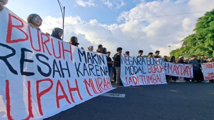 MEMBENTANGKAN SPANDUK, Massa mahasiswa dari Aliansi Mahasiswa Bergerak menggelar aksi orasi dalam rangka hari buruh internasional di depan alun-alun Purwokerto, Kamis (1/5/2025).