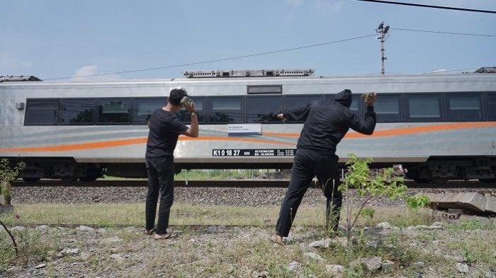 Ilustrasi pelemparan batu ke arah kereta api yang melintas.