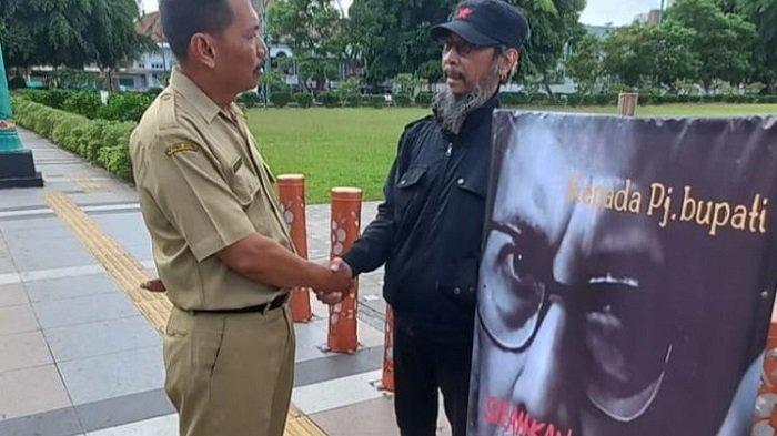 Seniman Banyumas Surya Esa ditemuai Pranata Bagian Prokompim Setda Banyumas, Prasito, di depan kantor bupati, Senin (1/4/2024). Esa menggelar aksi protes tunggal di pintu gerbang kantor Bupati Banyumas karena keinginan berdiskusi soal kenaikan harga beras tak direspon Pj Bupati Banyumas Hanung Cahyo Saputro.