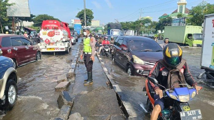 Anggota Unit Lantas Polsek Genuk mengatur lalu lintas yang padat merayap akibat banjir di jalur pantura Terboyo Kaligawe, Genuk, Kota Semarang, Sabtu (6/4/2024) pagi. Kedalaman genangan air 20-40 sentimeter sehingga masih dapat dilalui pengguna jalan.