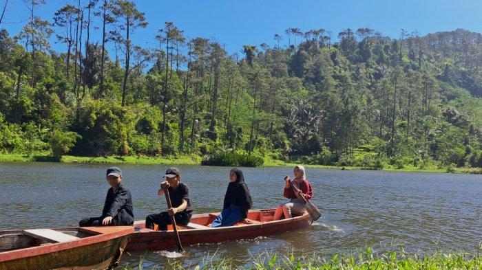 Pengunjung menikmati keindahan alam sembari menaiki perahu kayu yang disewa di Telaga Kumpe, Banyumas, Sabtu (15/7/2023).