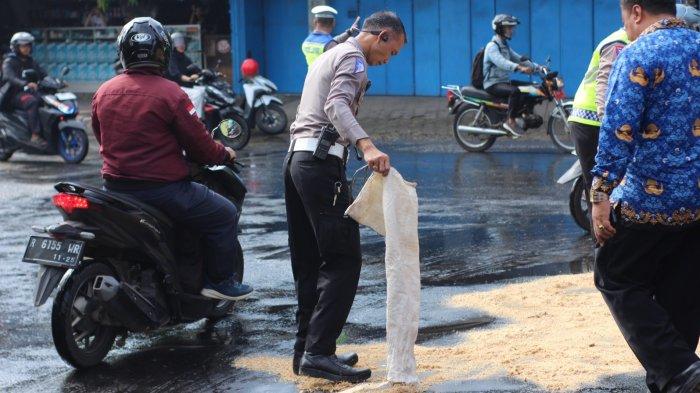 Petugas Satlantas Polres Purbalingga membersihkan tumpahan minyak di Jalan dekat Tugu Knalpot, Purbalingga, Rabu (29/11/2023). Petugas juga menggunakan serbuk kayu untuk menutup tumpahan minyak tersebut.