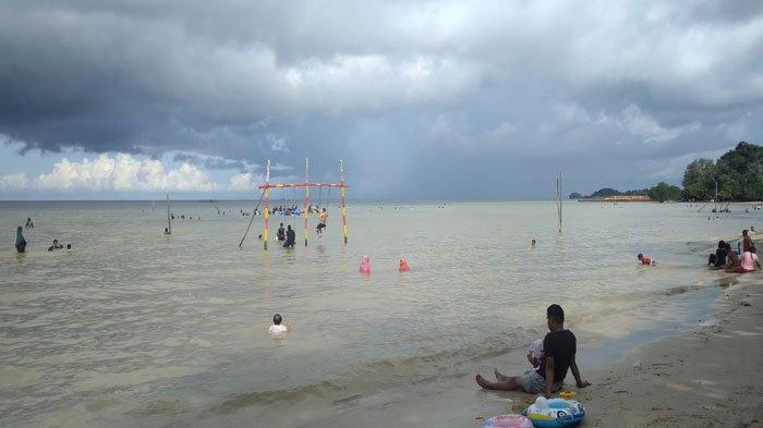 Pengunjung sedang menikmati bermain air di Pantai Tegar Bahari. Pantai ini termasuk destinasi wisata Batam yang menawarkan hamparan pasir putih.