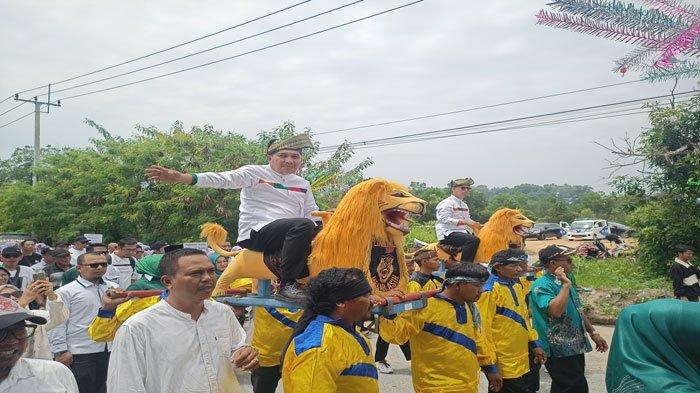 PILKADA KARIMUN 2024 - Calon Bupati dan Wakil Bupati Karimun, Ing Iskandarsyah-Rocky Marciano Bawole menunggangi sisingaan yang ditandu oleh empat orang menuju Kantor KPU Karimun untuk mendaftar ikut Pilkada, Kamis (29/8/2024).