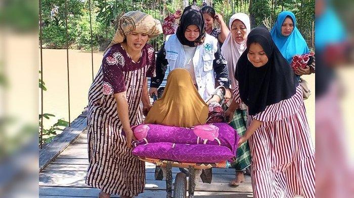 Bidan desa bersama warga mendorong gerobak yang angkut ibu hamil hendak melahirkan.
