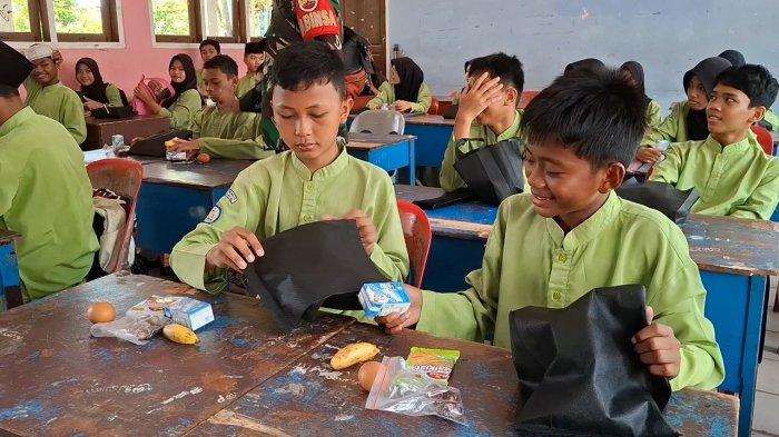 MBG - Salah seorang siswa SMP N 12 Batam, Fauzan saat hendak memindahkan menu MBG ke tempat bekal yang dibawa dari rumah, Jumat (7/3/2025).