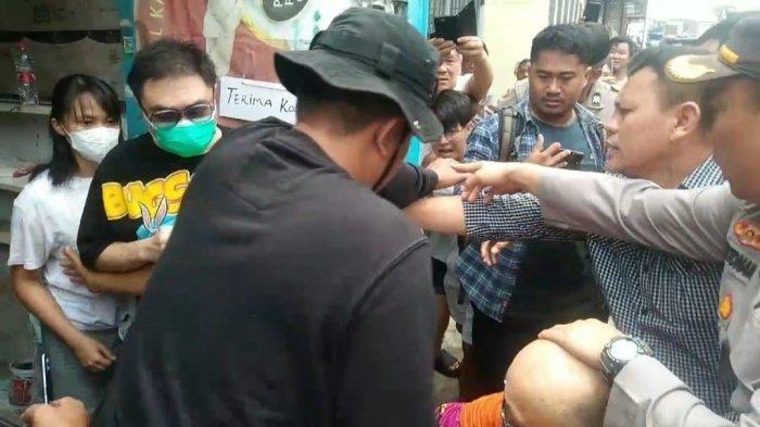 Kapolsek Medan Area, Kompol Hendrik Fernandes Aritonang (kanan), menenangkan situasi saat pelaku pembunuhan nyaris dihajar keluarga korban di lokasi kejadian, Jalan Badak, Kecamatan Medan Area, Senin (18/11/2024).
