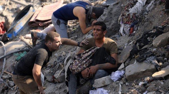 Seorang pria bereaksi sambil menggendong jenazah ibunya yang terbungkus selimut di tengah reruntuhan bangunan yang hancur dalam serangan Israel di kamp pengungsi Bureij di Jalur Gaza tengah pada 2 November 2023, saat pertempuran antara Israel dan gerakan Hamas Palestina masih berlanjut.