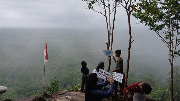 BUKIT BEGANDI - Pengunjung berada di area spot foto dan lokasi menikmati sunset di puncak Bukit Begandi, Dusun Kepayang, Desa Kacang Butor, Kecamatan Badau, Kabupaten Belitung, Provinsi Kepulauan Bangka Belitung, Minggu (18/5/2025).