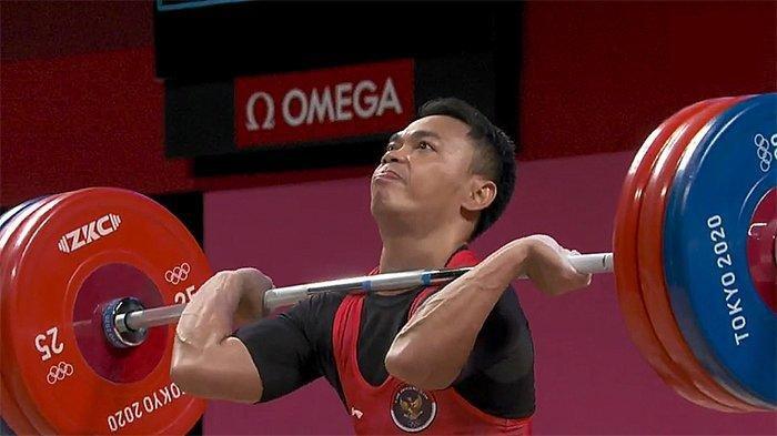 Eko Yuli Irawan sedang berusaha mengangkat besi di kejuaraan angkat besi Olimpiade Tokyo, Minggu (25/7/2021).
