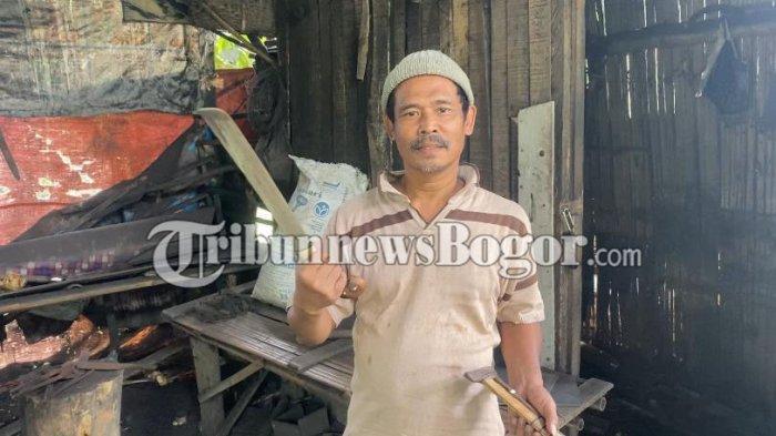 Romli, pemilik kerajinan Golok Panjaungan di Kampung Pabuaran Tonggoh, Desa Kalong 1, Kecamatan Leuwisadeng, Kabupaten Bogor memegang hasil produksinya, Selasa (13/8/2024). (Muamarrudin Irfani)
 
 