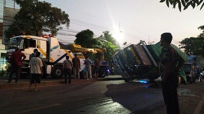 Petugas melakukan evakuasi truk tronton yang terguling menimpa mobil pikap di Jalan Raya Bogor, Cimanggis, Kota Depok, Rabu (20/12/2023).