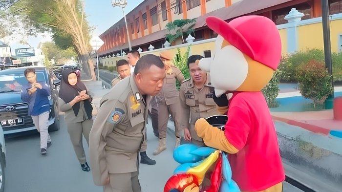 Seorang Satpol PP Kota Gorontalo berkomunikasi dengan badut di jalanan. 