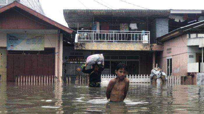 Seorang bocah laki-laki berjalan di tengah banjir bandang di Kelurahan Heledulaa Selatan, Kota Timur, Kota Gorontalo, Kamis (11/7/2-24).