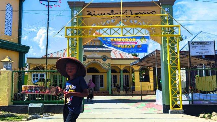 GEBYAR KETUPAT - Seorang anak tampak memegang dus untuk sumbangan kegiatan Semarak gebyar ketupat di Kelurahan Moodu, Kecamatan Kota Timur, Kota Gorontalo, Sabtu (12/4/2025).