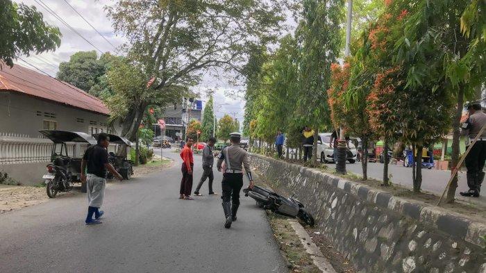 HINDARI RAZIA -- Potret personel polisi dan warga berusaha membantu siswa yang mengalami kecelakaan di Jalan Pangeran Hidayat, Kota Gorontalo, pada Selasa (15/7/2025). Siswa itu menghindari razia polisi hingga nyaris menabrak beton pembatas jalan.