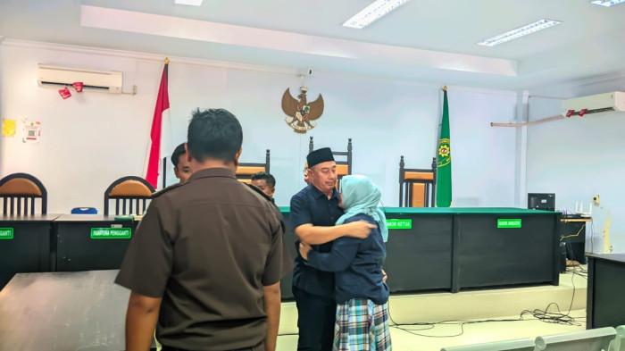 VONIS HAKIM -- Hamim Pou, eks Bupati Bone Bolango, Gorontalo, tampak memeluk istrinya di ruang sidang usai putusan dijatuhkan hakim, Rabu (23/7/2025).