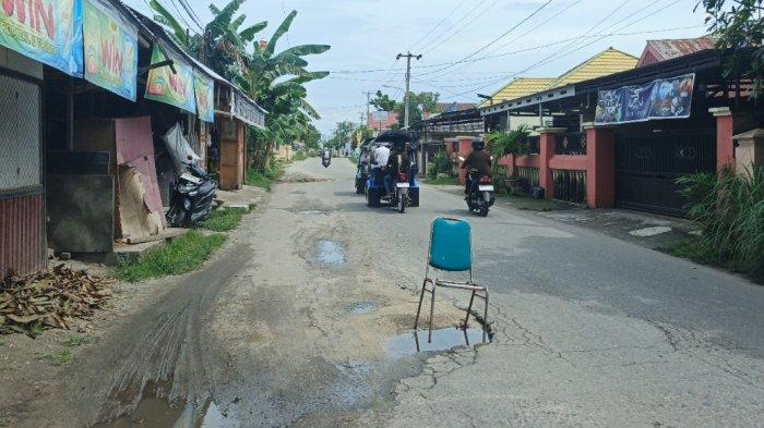 JALAN RUSAK — Warga menaruh kursi di Jl KH Adam Zakaria. Warga setempat mengeluhkan kondisi jalan berlubang yang kerap jadi penyebab kecelakaan.