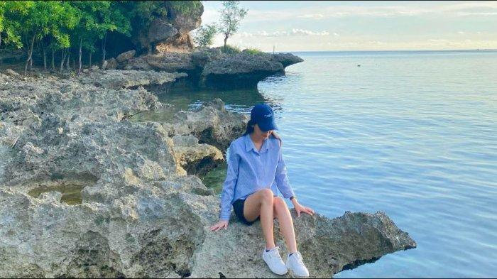 Wisatawan mengabadikan momen di atas karang Pantai Oluhuta, Minggu (10/11/2024).