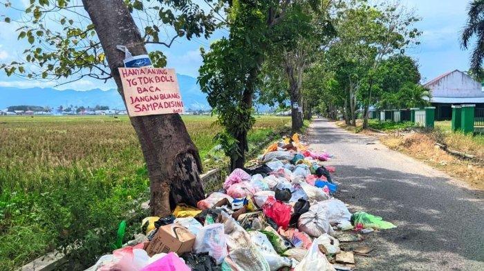TUMPUKAN SAMPAH - Ada tumpukan sampah di bibir jalan Wongkaditi, Kota Gorontalo, Senin (17/2/2025). Sampah ini disebut berasal dari orang-orang luar wilayah tersebut. Apalagi ini bukan tempat sampah. Warga yang resah pun buat tulisan memaki.
