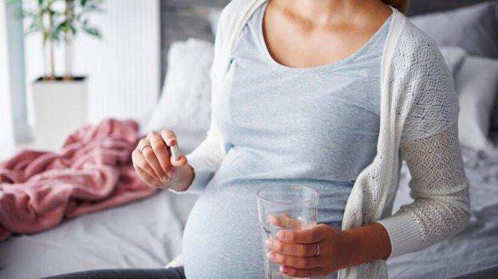 Ilustrasi ibu hamil yang mengonsumsi vitamin prenatal untuk menambah berat badan janin