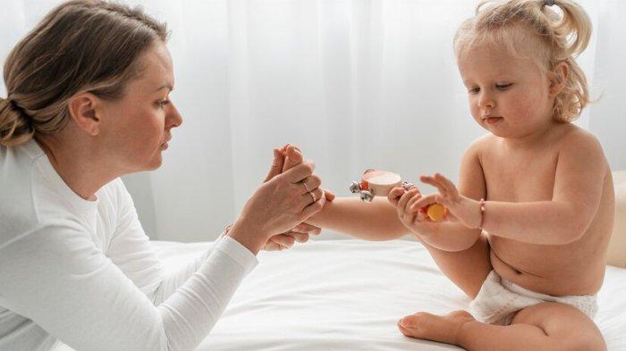 Ilustrasi seorang ibu yang mengoleskan baby oil kepada buah hatinya, berikut manfaat baby oil untuk bayi