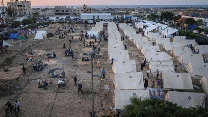 Warga Palestina menghuni kamp tenda sementara yang didirikan untuk mereka yang terpaksa mengungsi dari rumah mereka akibat perintah evakuasi dan serangan udara Israel, di Khan Younis, Jalur Gaza selatan.