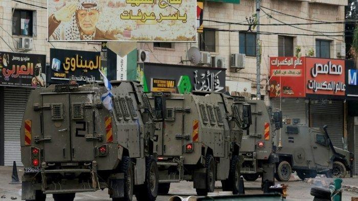 Kendaraan tentara Israel melaju melalui distrik komersial setelah jam malam diberlakukan di Tulkarem selama operasi militer di kota Tepi Barat yang diduduki pada 14 November 2023.