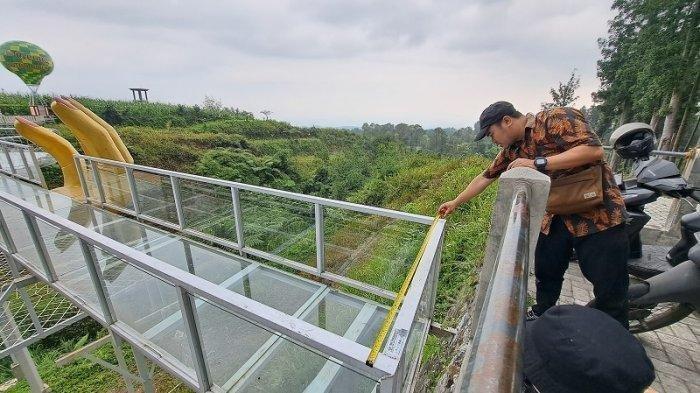 Petugas Dinas Pekerjaan Umum (DPU) Kabupaten saat memeriksa jenis kaca yang digunakan pada Jembatan kaca The Geong di Hutan Pinus Limpakuwus, Rabu (25/10/2023).