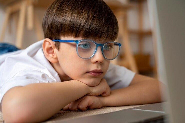 ilustrasi seorang anak yang menggunakan kacamata saat menatap layar laptop