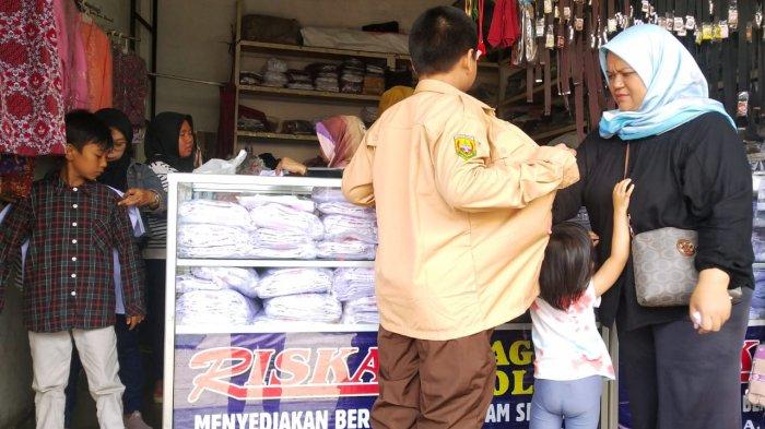 Orang tua membelikan seragam sekolah untuk anaknya di salah satu toko perlengkapan seragam sekolah, di Jalan Cipaera, Kosambi, Kota Bandung, Jawa Barat, Senin (10/7/2023).