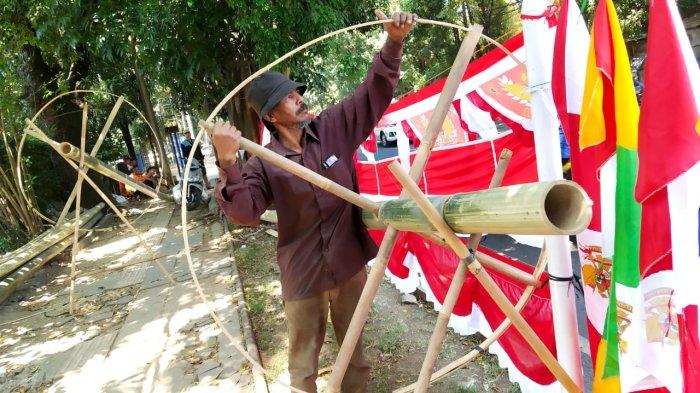 Alamsyah (56), memasang bilah bambu melingkar di ujung batang bambu tali/apus saat membuat bambu panjat pinang di Jalan Moch. Toha, Kota Bandung, Jawa Barat, Senin (14/8/2023).