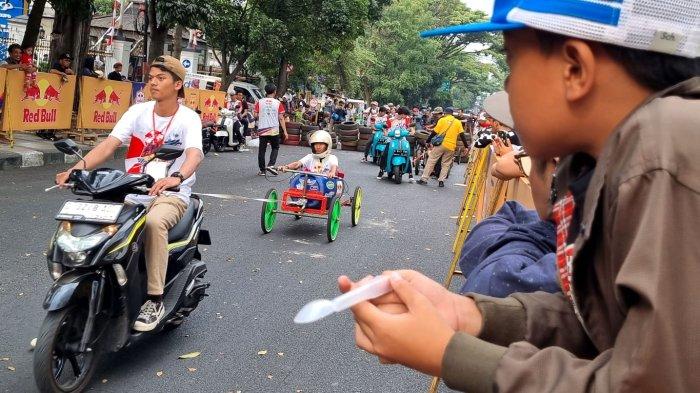 Panitia menggunakan sepeda motor menarik kereta yang baru selesai lomba dalam Lomba Kereta Peti Sabun (LKPS) Kesepuluh 2023 Jalan Diponegoro, Kota Bandung, Jawa Barat, Sabtu (26/8/2023).