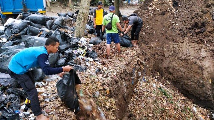 Petugas Ranger Dinas Perumahan dan Kawasan Permukiman (DPKP) Kota Bandung memasukan sampah organik jenis daun-daunan ke lubang yang baru selesai dibuat di area Taman Tegallega, Kota Bandung, Jawa Barat, Rabu (30/8/2023).