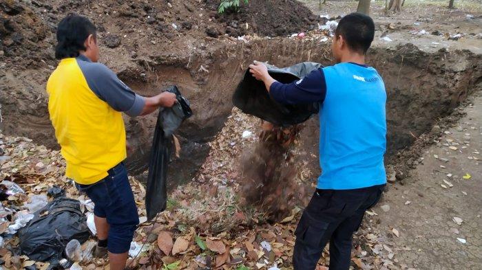 Petugas Ranger Dinas Perumahan dan Kawasan Permukiman (DPKP) Kota Bandung memasukan sampah organik jenis daun-daunan ke lubang yang baru selesai dibuat di area Taman Tegallega, Kota Bandung, Jawa Barat, Rabu (30/8/2023).