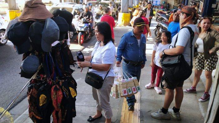 Wisatawan berbelanja topi dan ikat kepala khas Sunda saat mengunjungi kawasan wisata belanja di Jalan Cihampelas, Kota Bandung, Jawa Barat, Kamis (28/9/2023).