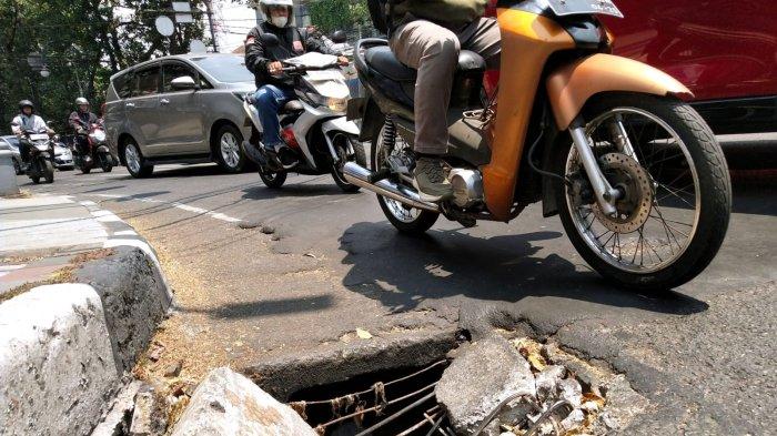 Pengendara bermotor melintasi tembok beton penutup gorong-gorong yang pecah di belokan sisi kanan jalan persimpangan Jalan Merdeka dan Jalan LLRE Martadinata, Kota Bandung, Jawa Barat, Selasa (10/10/2023).