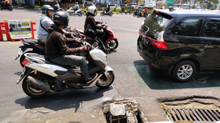 Pengendara bermotor melintasi tembok beton penutup gorong-gorong yang pecah di belokan sisi kanan jalan persimpangan Jalan Merdeka dan Jalan LLRE Martadinata, Kota Bandung, Jawa Barat, Selasa (10/10/2023).