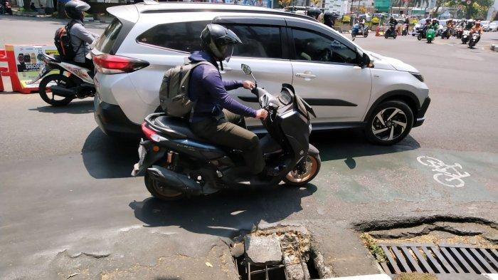 Pengendara bermotor melintasi tembok beton penutup gorong-gorong yang pecah di belokan sisi kanan jalan persimpangan Jalan Merdeka dan Jalan LLRE Martadinata, Kota Bandung, Jawa Barat, Selasa (10/10/2023).