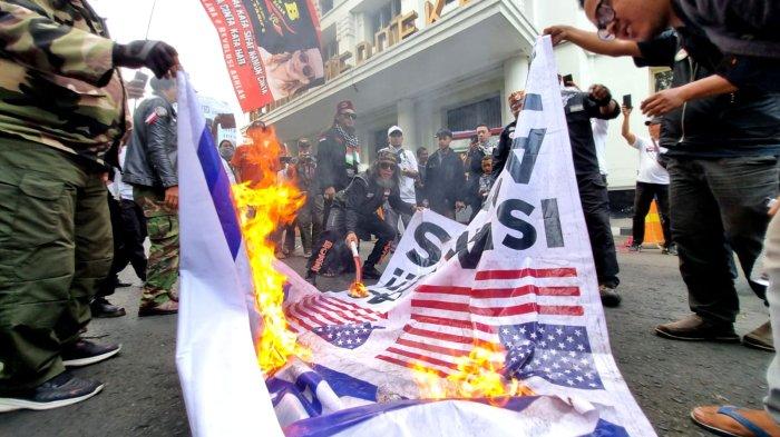 Massa Aksi Jawa Barat Dukung Palestina membakar baliho bergambar bendera Israel dan Amerika Serikat, di depan Gedung Merdeka, Jalan Asia Afrika, Kota Bandung, Jawa Barat, Sabtu (21/10/2023).