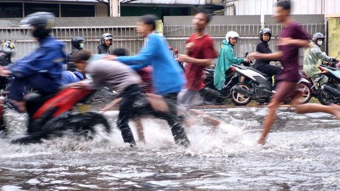 Sejumlah warga mendorong sepeda motor yang mogok saat menerjang banjir cileuncang yang merendam Jalan Kopo Citarip, Kelurahan Kopo, Kecamatan Bojongloa Kaler, Kota Bandung, Jawa Barat, Selasa (24/10/2023).